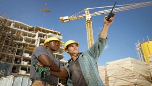 Two Builders on a Building Site, with One Man Pointing with a Walkie Talkie